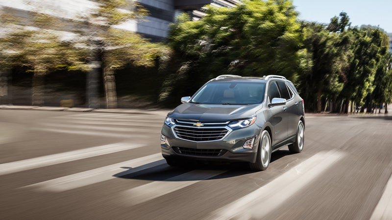 Chevrolet Equinox driving on a road, showcasing its sleek design as it moves along a smooth, open highway with a scenic background