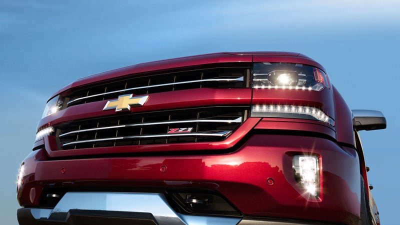 Front view of a red Chevrolet Silverado 1500, highlighting its bold grille, aggressive headlights, and rugged design