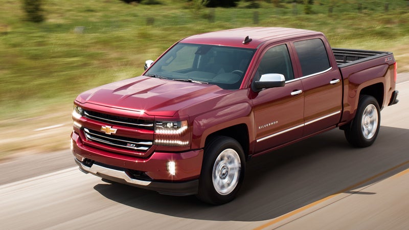 A red Chevrolet Silverado 1500 driving on a road, displaying its rugged design and powerful presence