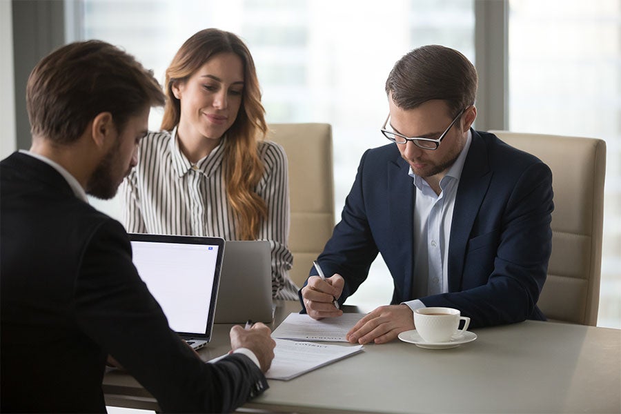 Couple and salesman signing paperwork at table